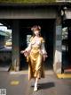 A woman in a yellow kimono is walking down the street.