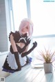 A woman in a maid outfit sitting on a table next to a plant.