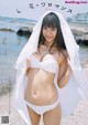 A woman in a white bikini standing on a beach.