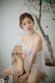 A woman in a white lingerie sitting on a chair.
