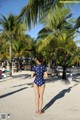 A woman in a polka dot swimsuit standing on a beach.