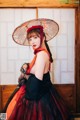 A woman in a black and red dress holding an umbrella.