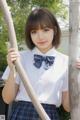 A young woman in a school uniform holding a wooden stick.