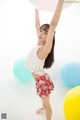 A young woman holding a bunch of balloons in the air.