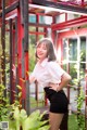 A woman in a white shirt and black skirt posing for a picture.