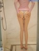 A woman in a pink shirt is standing in a shower.