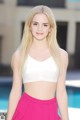 A woman in a white top and pink skirt posing by a pool.