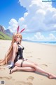 A woman in a bunny suit sitting on a beach.