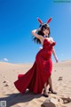 A woman in a red dress and bunny ears in the desert.