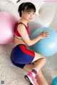 A young girl sitting on the floor with two exercise balls.